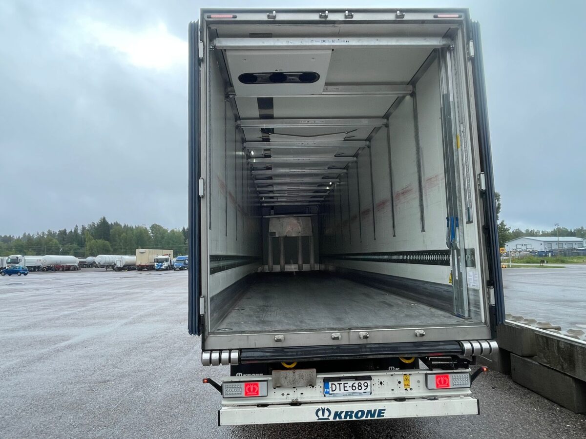 Tyhjä avolava-rekka on pysäköity ulkoilma-alueelle pilvisenä päivänä, ja kuvassa näkyy perävaunun sisätila. Rekisterikilvessä lukee DTE-689..